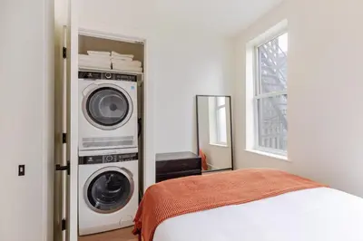 a bedroom with a washing machine next to a bed at Blueground Manhattan wd AC nr park NYC-1829 in New York