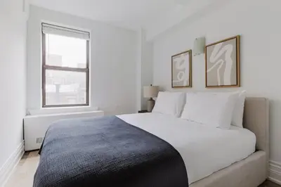 a white bedroom with a large bed and a window at Blueground Upper West Side fitness center nr Central Park NYC-1596 in New York