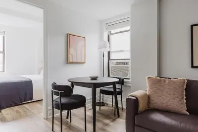 a room with a table and chairs and a bed at Blueground Upper West Side fitness center nr Central Park NYC-1596 in New York