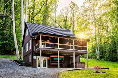 a house in the woods with a black roof at The River Shack - kayaks, fishing, quiet, family in Delta