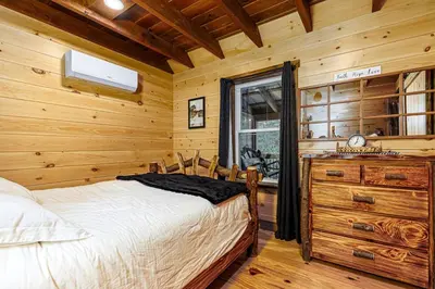 a bedroom with a bed and a window in a log cabin at The River Shack - kayaks, fishing, quiet, family in Delta