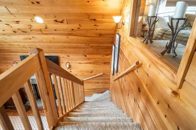 a staircase in a log home with wooden walls at Lazy River Cabin: Lakefront Stay in Greentown