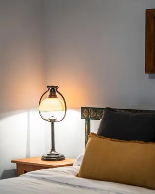 a lamp sitting on a table next to a bed at Lazy River Cabin: Lakefront Stay in Greentown