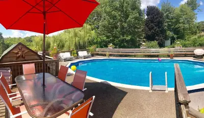 a pool with a table and a red umbrella at Honesdale Escape ~ A Place to Remember - Apartment in Honesdale