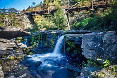 a waterfall in a river with a bridge in the background at Honesdale Escape ~ A Place to Remember - Apartment in Honesdale