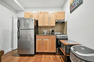 a kitchen with a stainless steel refrigerator and wooden cabinets at Cozy Modern Studio Perfect for Short or Long Stays in Philadelphia