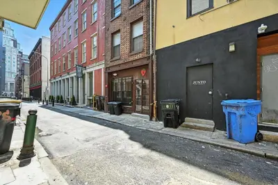 an empty city street with trash cans and buildings at Cozy Modern Studio Perfect for Short or Long Stays in Philadelphia