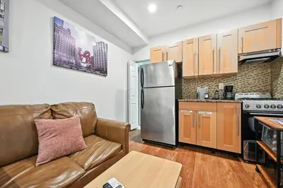 a living room with a couch and a stainless steel refrigerator at Cozy Modern Studio Perfect for Short or Long Stays in Philadelphia