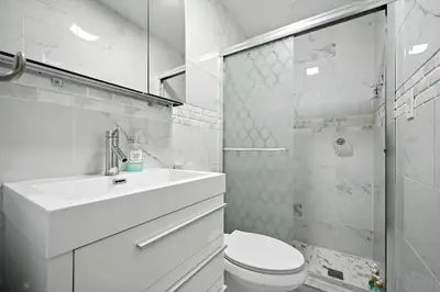 a white bathroom with a sink and a toilet at Cozy Modern Studio Perfect for Short or Long Stays in Philadelphia