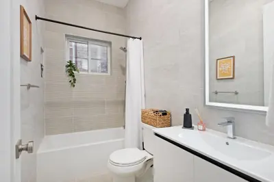a white bathroom with a toilet and a sink at Travelers Dream that's Mins to NYC having Game Room and Parking in Jersey City