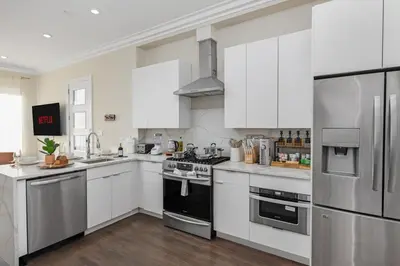 a kitchen with white cabinets and stainless steel appliances at Travelers Dream that's Mins to NYC having Game Room and Parking in Jersey City