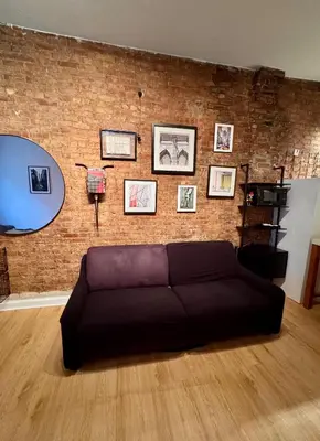 a living room with a couch in front of a brick wall at Gotham House in New York