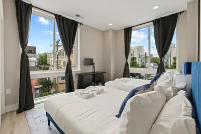 two beds in a room with large windows at Aparmint at Five on Canal - Philadelphia in Philadelphia