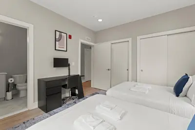 two beds in a room with a desk and a television at Aparmint at Five on Canal - Philadelphia in Philadelphia
