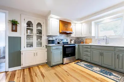 a kitchen with white cabinets and a stove top oven at Amish Guest House - hottub, patio, swing, ebikes in Gordonville