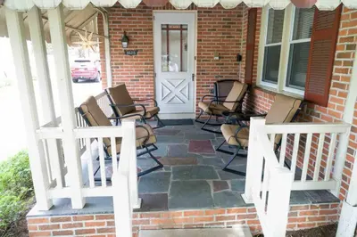 a group of chairs sitting on the front porch of a house at Amish Guest House - hottub, patio, swing, ebikes in Gordonville