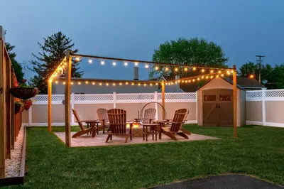 a patio with a table and chairs under a pergola with lights at Amish Guest House - hottub, patio, swing, ebikes in Gordonville
