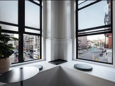 a room with three windows and a table and a street at CityNest Hotel in New York
