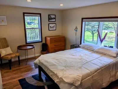 a bedroom with a bed and a chair and windows at Catskills Lakefront with Kayaks, HotTub & Firepit in Swan Lake