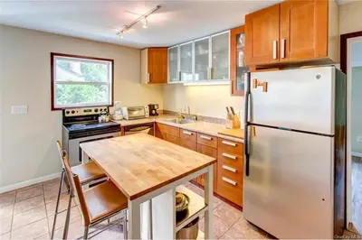 a kitchen with a stainless steel refrigerator and a wooden table at Catskills Lakefront with Kayaks, HotTub & Firepit in Swan Lake