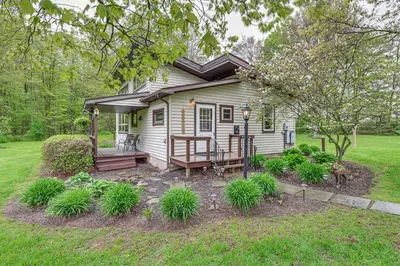 a small white house with a porch and a deck at Near State Parks Countryside Cottage in Wellsboro in Wellsboro