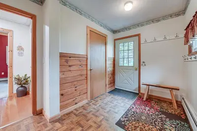 a hallway with a wooden door and a bench at Near State Parks Countryside Cottage in Wellsboro in Wellsboro