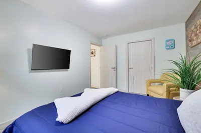 a bedroom with a blue bed with a tv on the wall at Apartment Minutes from Camelback Mountain with Washer Dryer in Tannersville