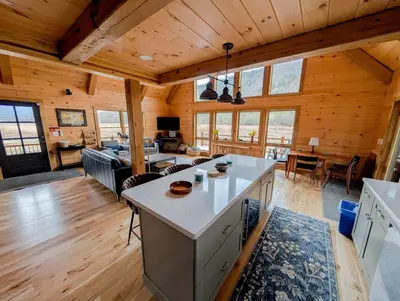 a kitchen and living room of a log cabin at Fully Loaded Riverfront West Branch Fishing Cabin in Deposit
