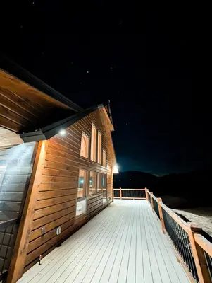 a wooden building with a deck at night at Fully Loaded Riverfront West Branch Fishing Cabin in Deposit