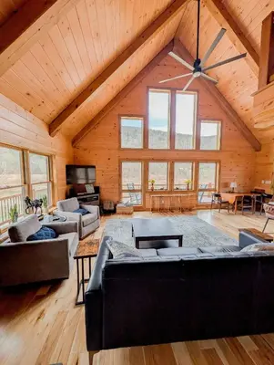 a large living room with wooden ceilings and windows at Fully Loaded Riverfront West Branch Fishing Cabin in Deposit