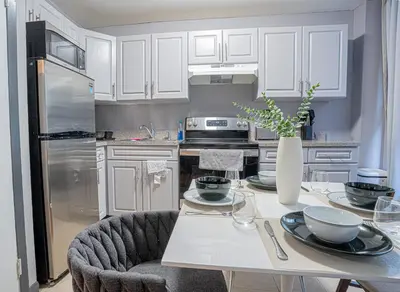 a kitchen with white cabinets and a table with a vase at Stylish 3BD Near Empire in New York