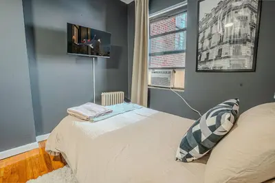a bedroom with a bed and a tv on the wall at Stylish 3BD Near Empire in New York