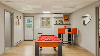 a room with a ping pong table and orange chairs at Emerald Bluff by AvantStay Lake Views Deck Fire Pit Game Room in Long Pond