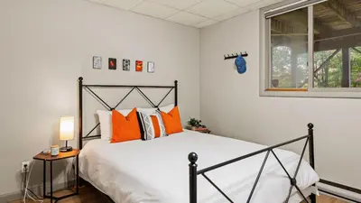 a bedroom with a bed with orange pillows and a window at Emerald Bluff by AvantStay Lake Views Deck Fire Pit Game Room in Long Pond