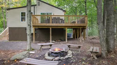 a house with a deck and a fire pit at Moshannon Tree-Lined Pocono Retreat w Hot Tub Firepit Pool Table in Pocono Lake