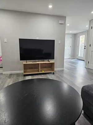 a living room with a flat screen tv and a table at Charming Twin Ponds Estate On 27 Acres in Woodbourne