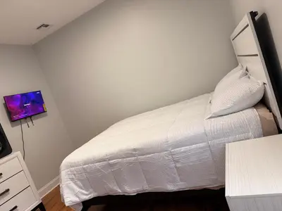 a bedroom with a white bed and a tv at E&G homes in East Orange