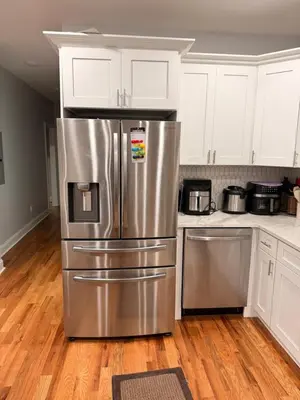 a kitchen with a stainless steel refrigerator and white cabinets at E&G homes in East Orange