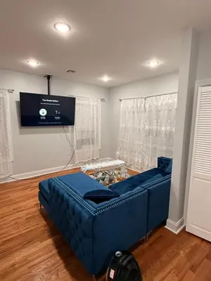 a living room with a blue couch and a flat screen tv at E&G homes in East Orange