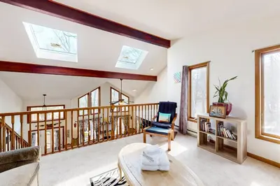 a living room with a staircase and a chair at Burntwood Retreat in East Stroudsburg