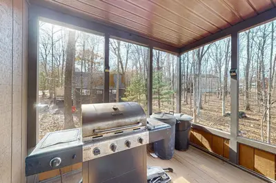 a screened in porch with a grill and windows at Burntwood Retreat in East Stroudsburg
