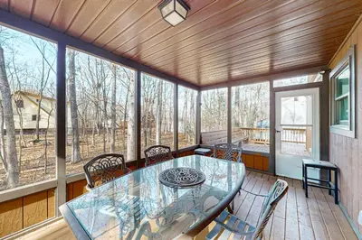 a screened in porch with a glass table and chairs at Burntwood Retreat in East Stroudsburg