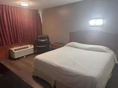a hotel room with a bed and a chair at Farrington Inn - North Brunswick in North Brunswick