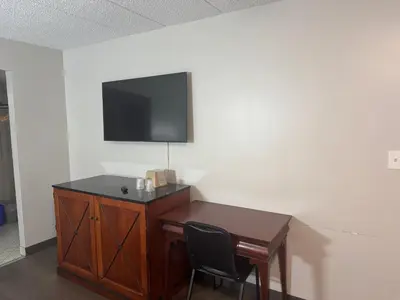 a room with a desk and a television on a wall at Farrington Inn - North Brunswick in North Brunswick