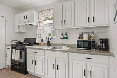 a white kitchen with a sink and a microwave at Fun Family getaway - NYC & NWK w free parking in Newark