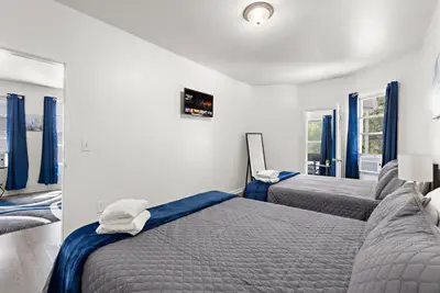 two beds in a bedroom with blue curtains at Fun Family getaway - NYC & NWK w free parking in Newark