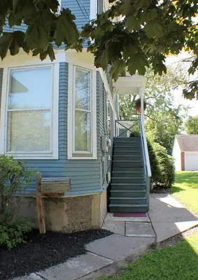 a blue house with a staircase leading up to a window at The White Birch Inn in Berwick
