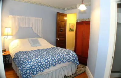 a bedroom with a bed with a blue and white blanket at The White Birch Inn in Berwick