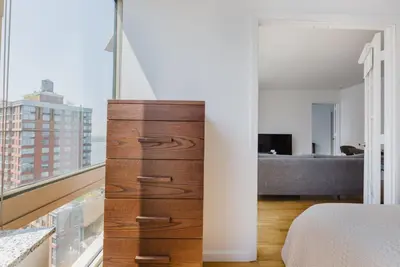 a bedroom with a dresser and a large window at Blueground Battery Park City rooftop nr Hudson River NYC-291 in New York
