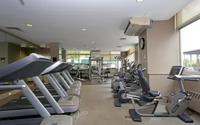 a gym with rows of treadmills and cardio machines at Blueground Battery Park City rooftop nr Hudson River NYC-291 in New York